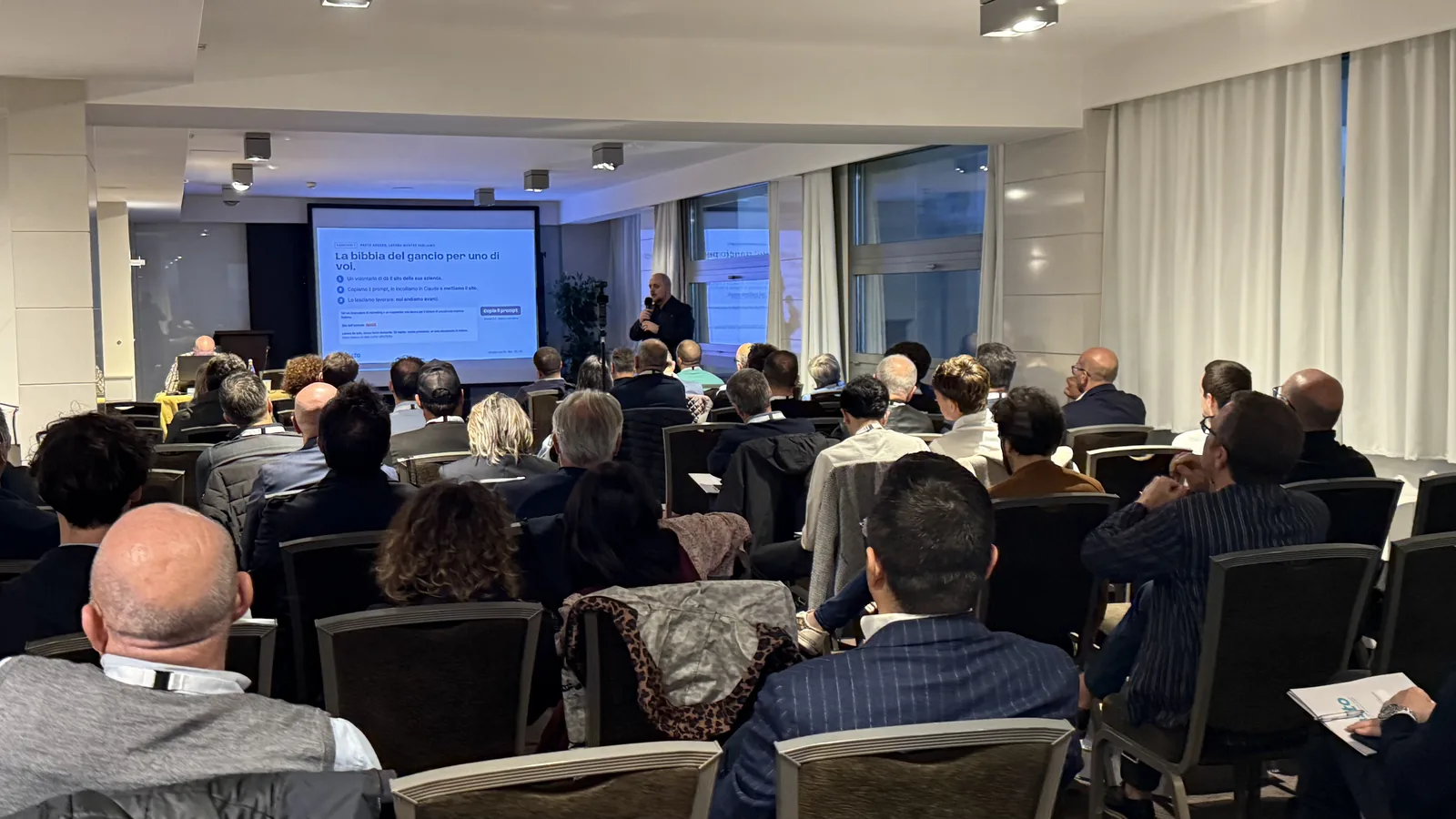 La platea piena a Bari, con il relatore e lo schermo in fondo alla sala
